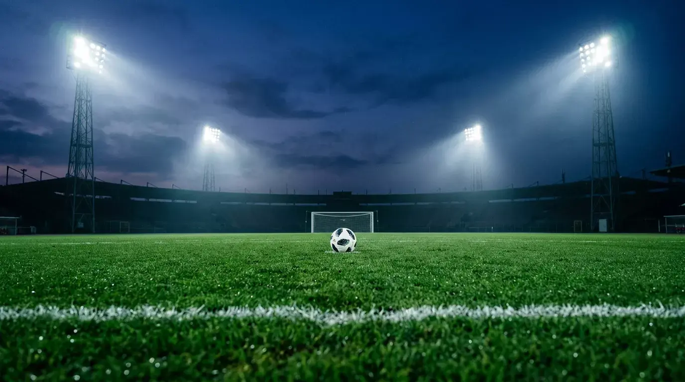 Fodboldstadion i tusmørke med græsset oplyst af projektører