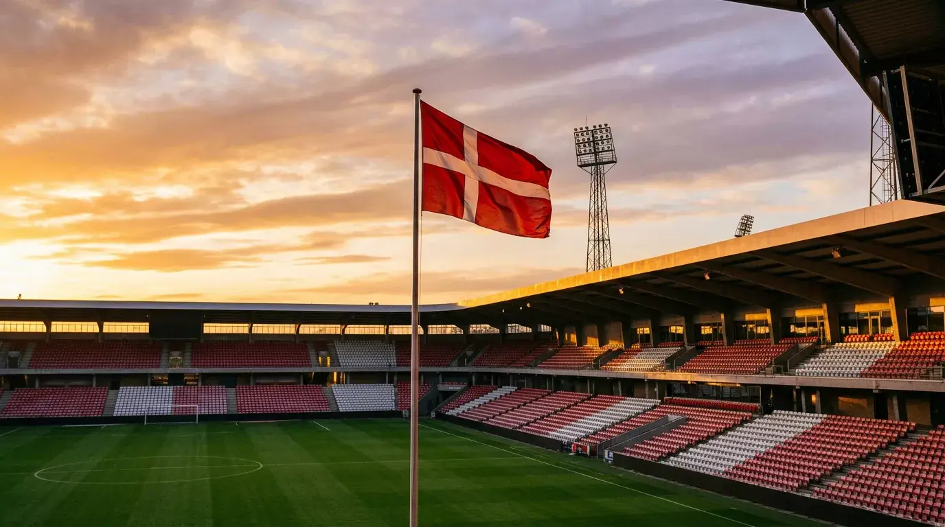 Tom stadiontribune ved solnedgang med Dannebrog vajende i vinden